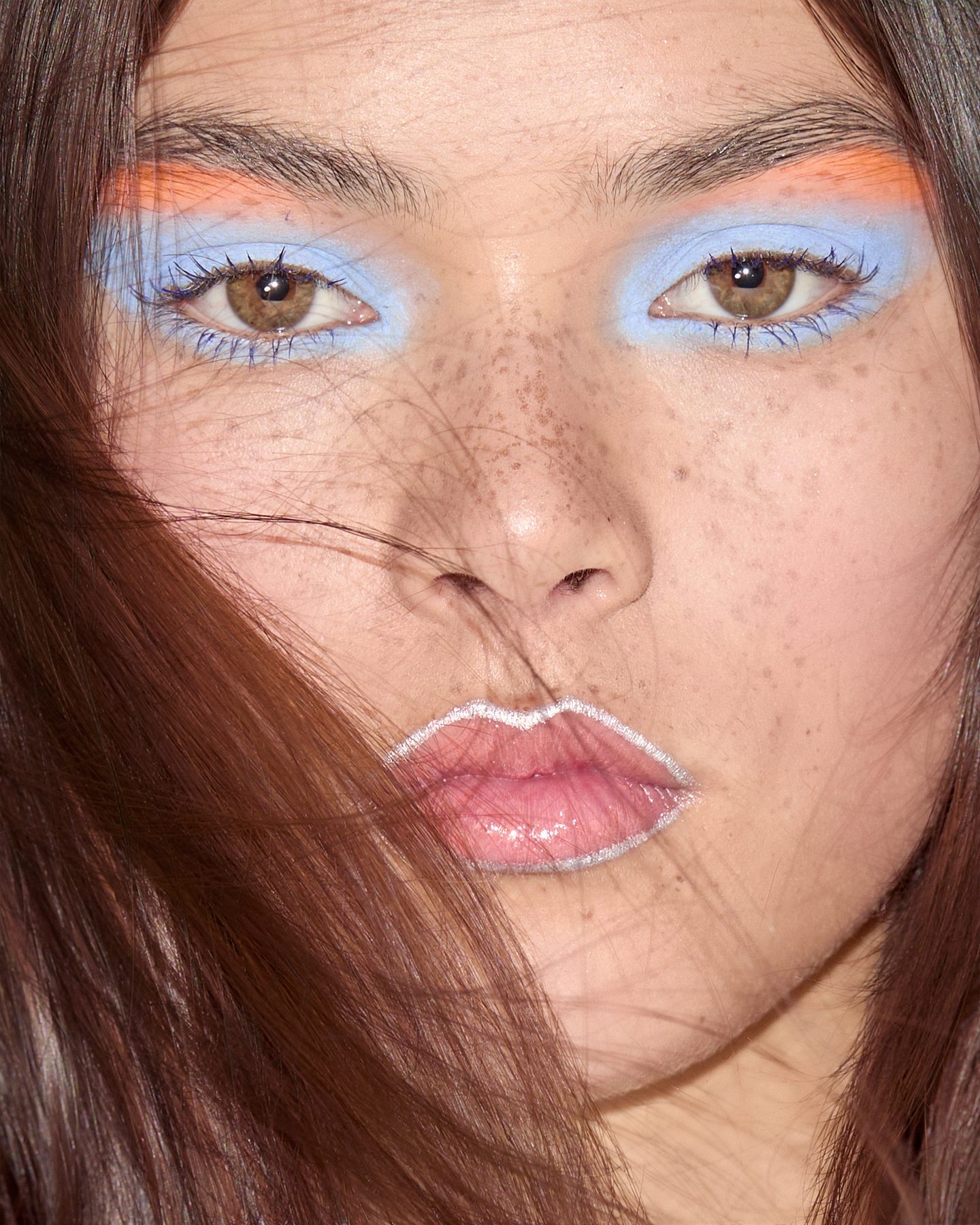 Bold blue and orange editorial eye makeup on a freckled face, makeup by Sydney Taeko